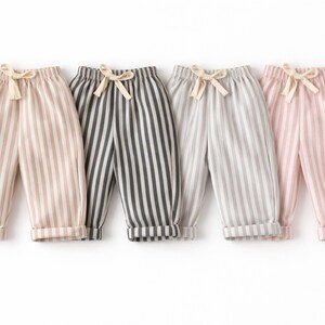 Puede incluir: Cuatro pantalones a rayas en beige, gris oscuro, gris claro y rosa. Cada par tiene rayas verticales, cintura con cord&oacute;n y dobladillos. Los pantalones est&aacute;n dise&ntilde;ados para ni&ntilde;os.