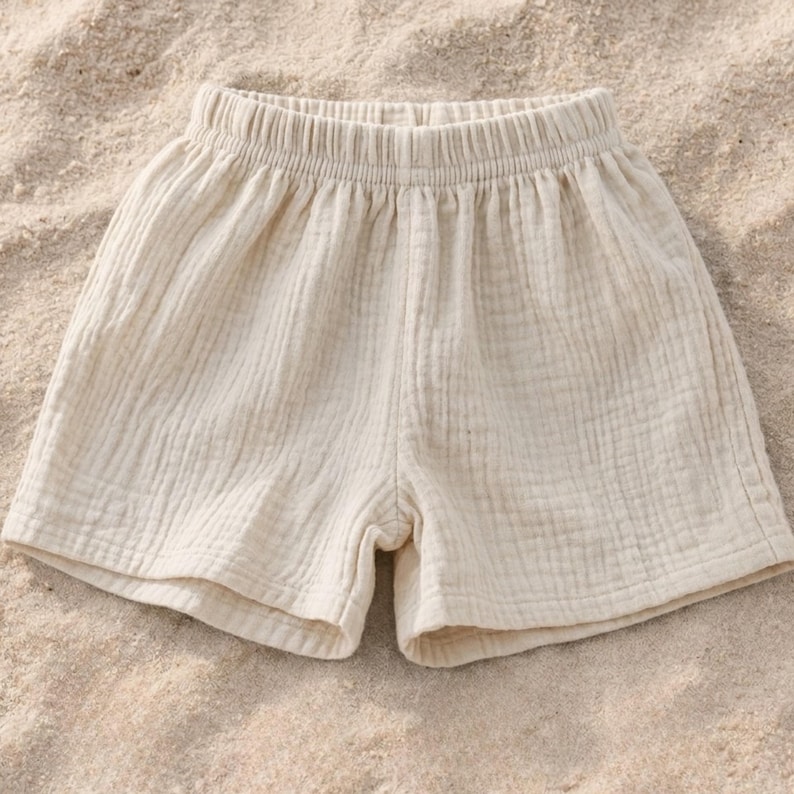 May include: Cream-colored shorts with an elastic waistband. The shorts are made of a textured fabric and appear lightweight. The garment is suitable for warm weather and casual wear.