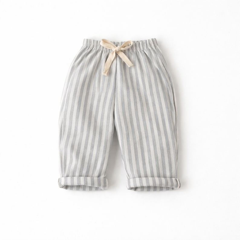 Puede incluir: Pantalones a rayas grises y blancas con cintura con cord&oacute;n y pu&ntilde;os doblados. Los pantalones informales est&aacute;n hechos de una tela suave. La paleta de colores neutros los hace vers&aacute;tiles.