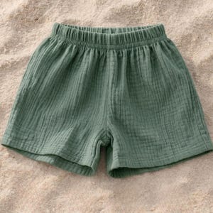 May include: Sage green shorts with an elastic waistband. The shorts are made of a textured, lightweight fabric. The garment is designed for comfort and casual wear.