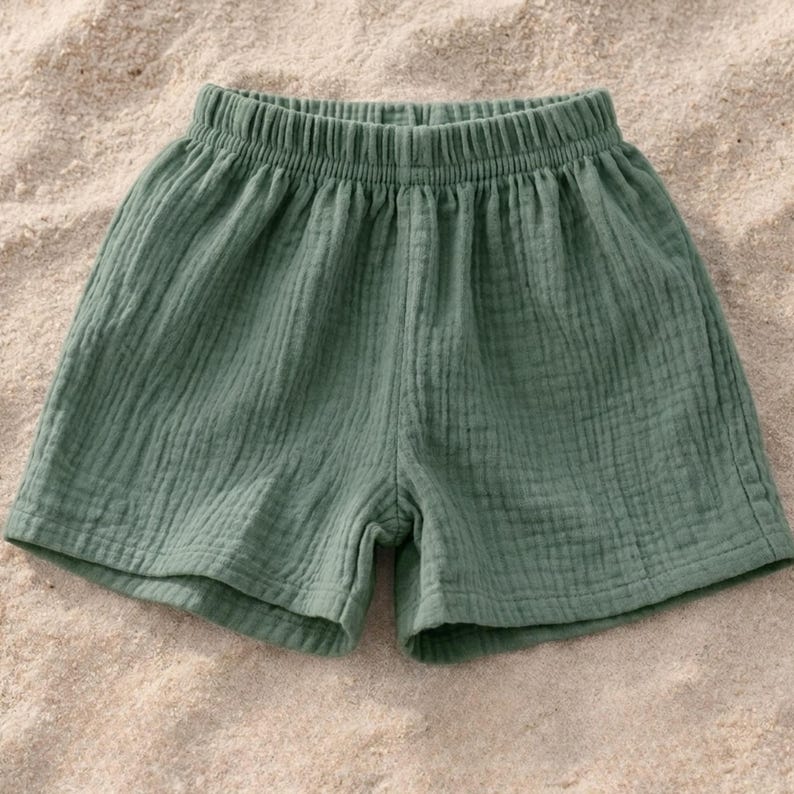 May include: Sage green shorts with an elastic waistband. The shorts are made of a textured, lightweight fabric. The garment is designed for comfort and casual wear.