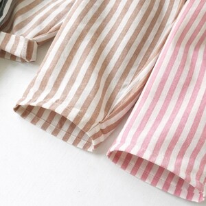 Puede incluir: Primer plano de tres pares de pantalones de pijama a rayas en diferentes colores. Un par es rosa y blanco, otro es marr&oacute;n y blanco, y el tercero es azul y blanco. La tela es suave y los pantalones tienen un corte holgado.