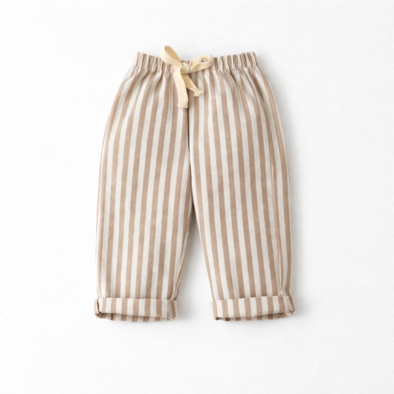 Puede incluir: Pantalones a rayas beige y blancas con cintura con cord&oacute;n y pu&ntilde;os doblados. Los pantalones informales est&aacute;n hechos de tela suave. Las rayas verticales crean un dise&ntilde;o visualmente atractivo. Adecuados para el uso diario.