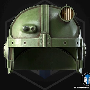 May include: A distressed green helmet with metal detailing and a circular light. The helmet features a rounded crown and side panels, hinting at a futuristic or military style. The overall appearance is aged and battle-scarred.