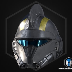 Puede incluir: Un casco futurista de metal gris oscuro con rayas amarillas. El casco presenta lentes de visera de color azul y un diseño angular complejo. El texto "GALACTIC ARMORY" es visible en el casco.