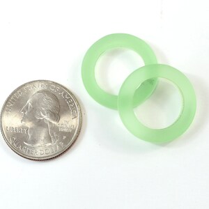 K&ouml;nnte beinhalten: Zwei gr&uuml;ne Glasringe, &auml;hnlich gro&szlig; wie eine US-amerikanische 25-Cent-M&uuml;nze.