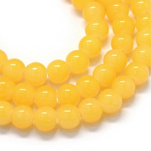 May include: A strand of yellow round beads. The beads are smooth and glossy.