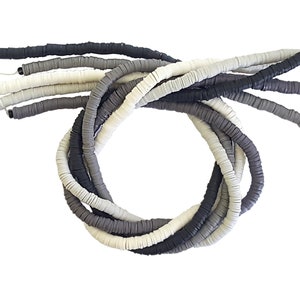 May include: A collection of gray, white, and black polymer clay beads. The beads are round and flat, and they are arranged in a gradient pattern.