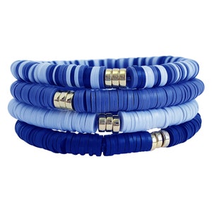 May include: A stack of four blue and light blue beaded bracelets with gold accents. The bracelets are made of round, flat beads.