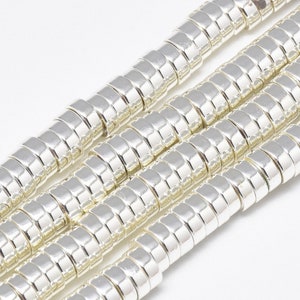 May include: A close-up of a silver metal bead chain. The beads are round and have a ridged texture. The chain is laid out in a straight line.