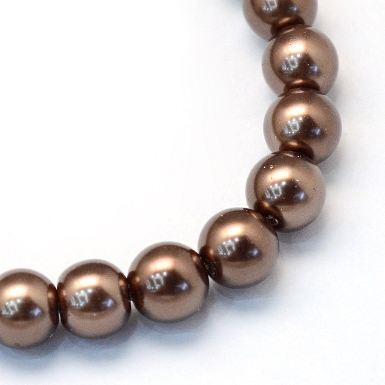 May include: A strand of brown faux pearl beads. The beads are round and have a smooth, glossy finish.