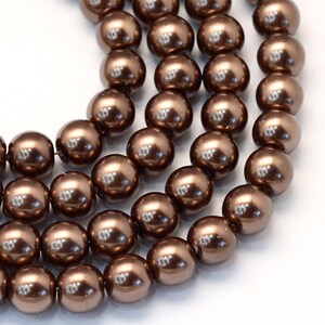 May include: A strand of brown pearl beads. The beads are round and have a glossy finish.