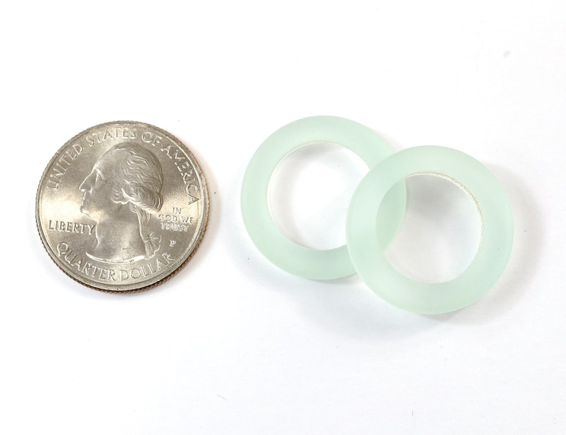 K&ouml;nnte beinhalten: Zwei gefrostete Glasringe in hellgr&uuml;ner Farbe. Die Ringe sind etwa so gro&szlig; wie eine US-amerikanische 25-Cent-M&uuml;nze.