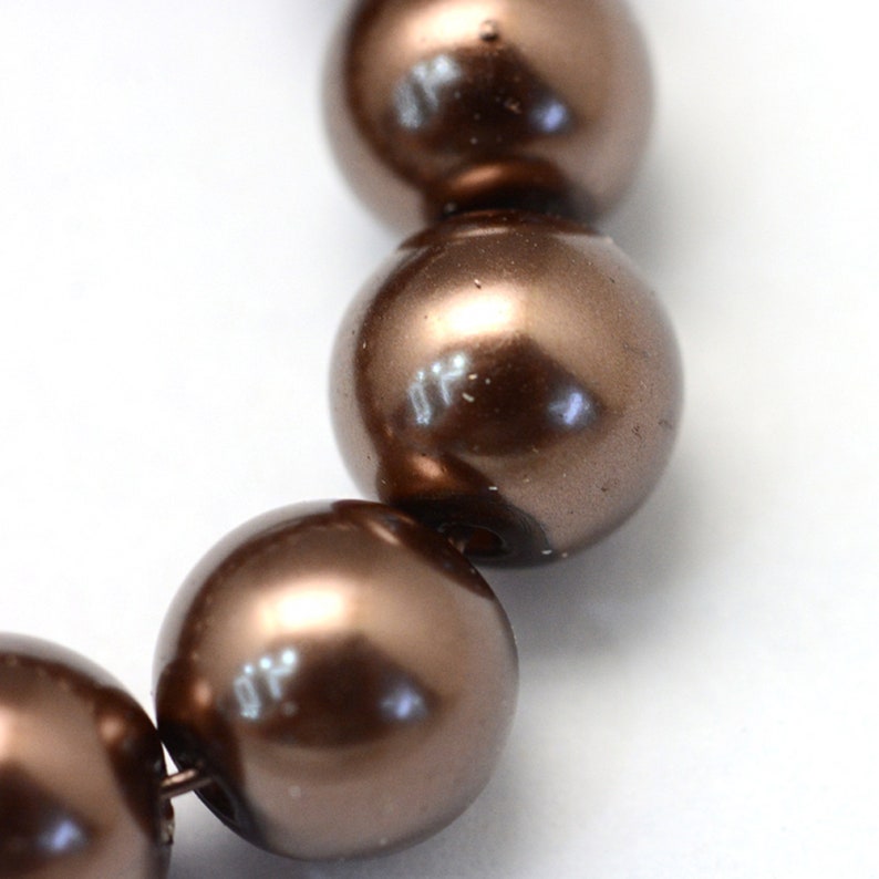 May include: A strand of brown pearl beads. The pearls are round and have a glossy finish.