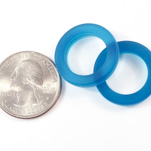 K&ouml;nnte beinhalten: Zwei blaue Glasringe, einer etwas gr&ouml;&szlig;er als der andere, auf wei&szlig;em Hintergrund. Die Ringe sind durchscheinend und haben eine matte Oberfl&auml;che.