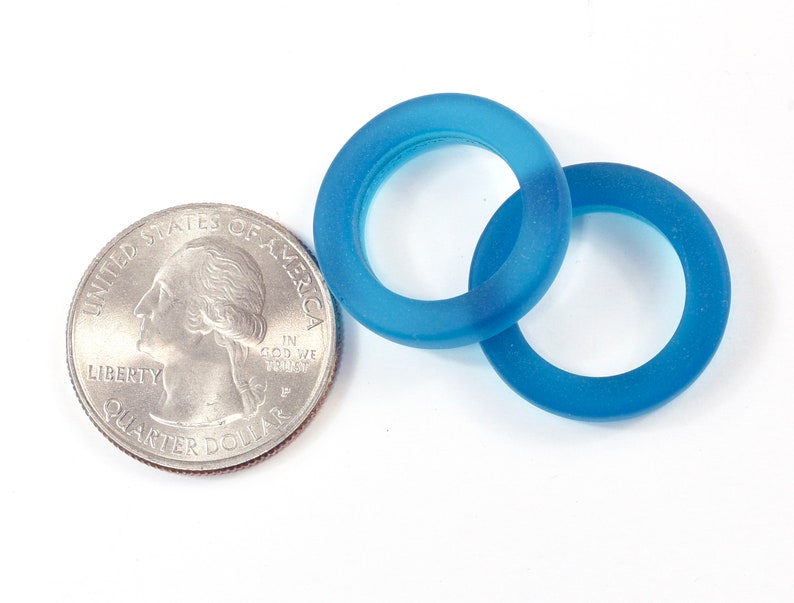 K&ouml;nnte beinhalten: Zwei blaue Glasringe, einer etwas gr&ouml;&szlig;er als der andere, auf wei&szlig;em Hintergrund. Die Ringe sind durchscheinend und haben eine matte Oberfl&auml;che.