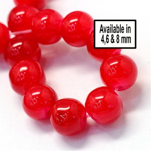 May include: Close-up of a strand of bright red round glass beads. Available in 4, 6, & 8 mm.
