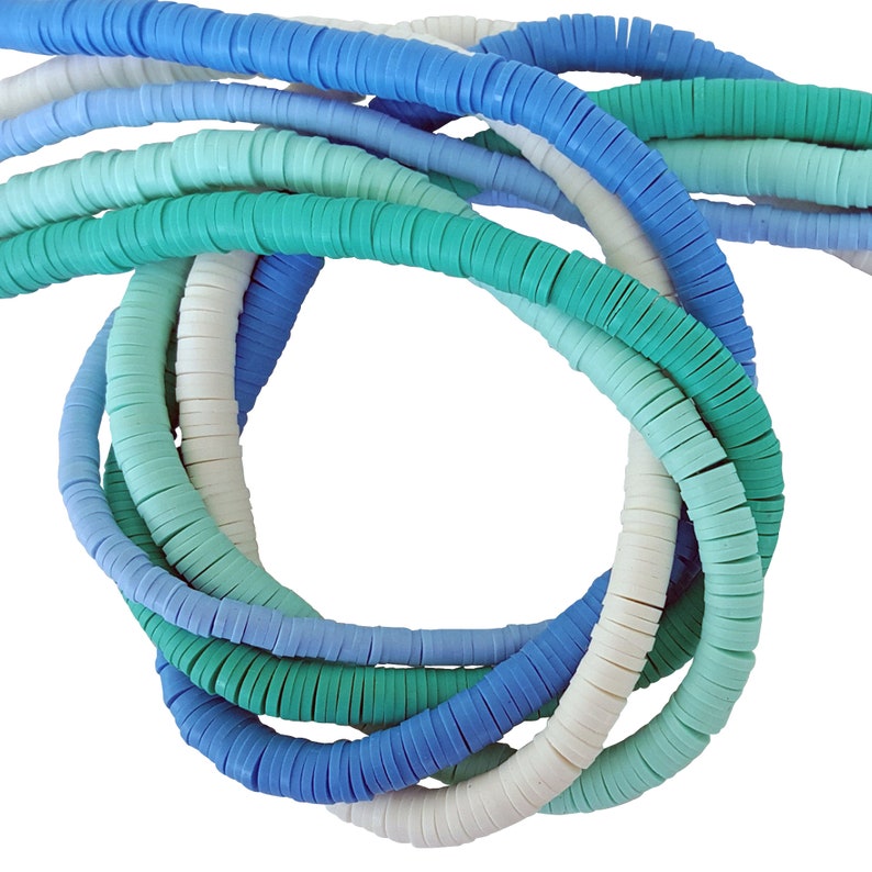 Pu&ograve; includere: Primo piano di un mucchio di perline rotonde di plastica colorate. Le perline sono in tonalit&agrave; di blu, verde e bianco. Le perline sono disposte in un motivo circolare, creando un effetto decorativo.