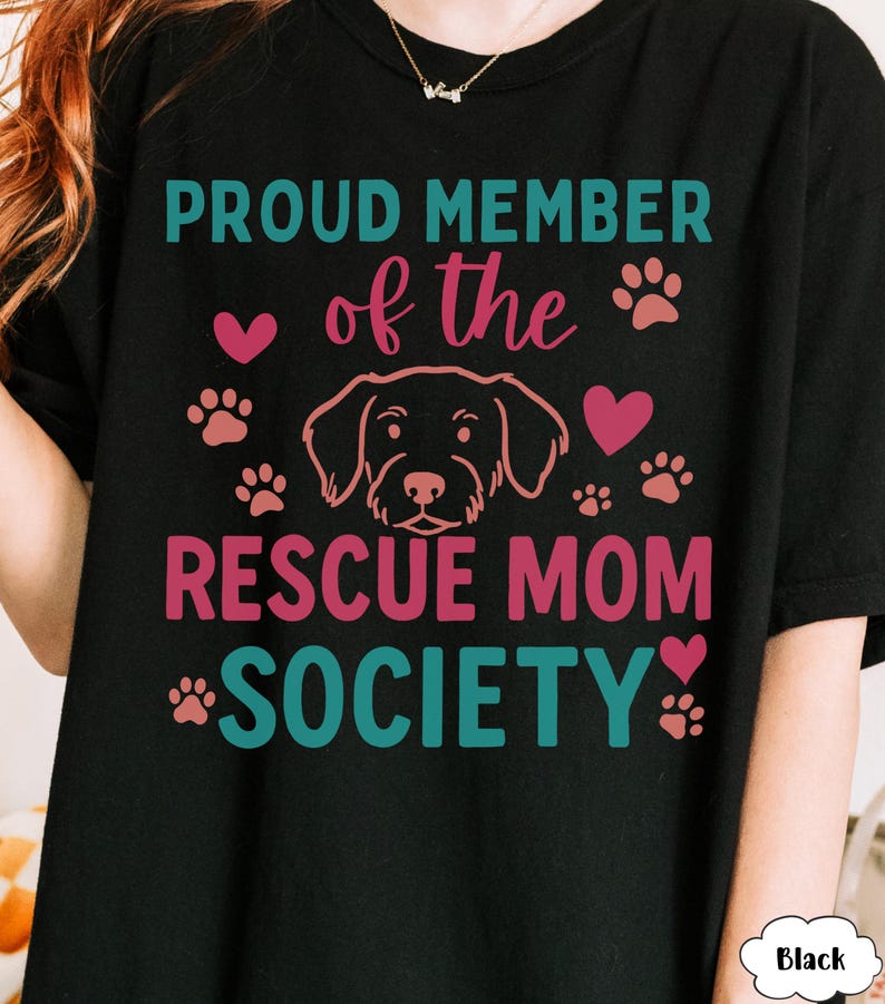 May include: Black t-shirt with the text "PROUD MEMBER of the RESCUE MOM SOCIETY" in teal and pink. The design includes a dog outline, paw prints, and hearts.