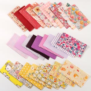 Può includere: Una collezione di campioni di tessuto in vari colori e motivi. I campioni includono disegni floreali, a pois e a righe in tonalità di rosso, rosa, viola, giallo e bianco. Alcuni campioni hanno un bordo smerlato.