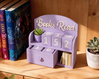 May include: A lavender wooden desk organizer with the words "Books Read" in white script. The organizer has a small drawer, a shelf with small books, and numbered blocks displaying "152". A small potted succulent sits on the top shelf.