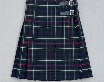 Falda escocesa de tartán verde y azul marino, chal plisado a cuadros, correas de cuero con hebilla, estilo Highland con flecos.