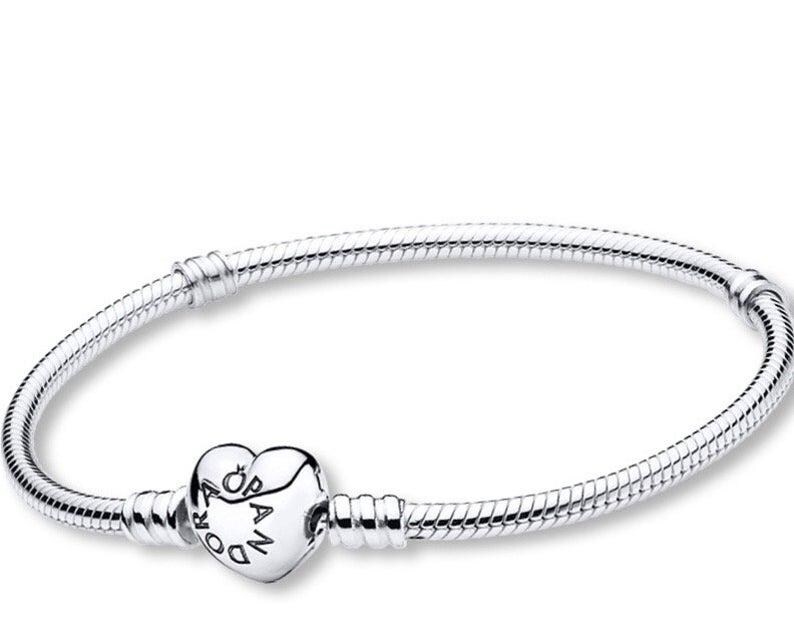 May include: A silver bracelet with a heart-shaped clasp. The bracelet features a snake chain design and a heart-shaped clasp with the word "Pandora" engraved on it. The bracelet is a piece of jewelry.