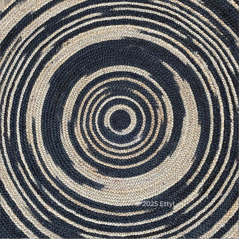 May include: Round jute rug with a spiral design. The rug features alternating concentric circles of navy blue and natural beige. The texture of the rug is visible, with the text "2025 Etty" in the lower right corner.