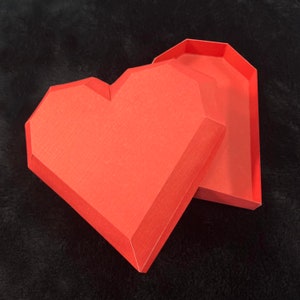Pu&ograve; includere: Una scatola a forma di cuore rossa con un coperchio. La scatola &egrave; fatta di cartone e ha una finitura testurizzata.