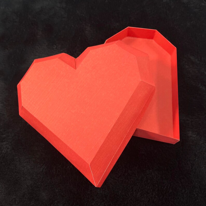 Pu&ograve; includere: Una scatola a forma di cuore rossa con un coperchio. La scatola &egrave; fatta di cartone e ha una finitura testurizzata.