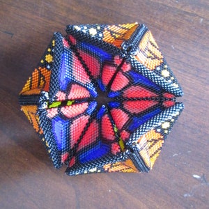 May include: A beaded, origami-style, geometric sculpture with a butterfly pattern in shades of red, orange, yellow, blue, and black.