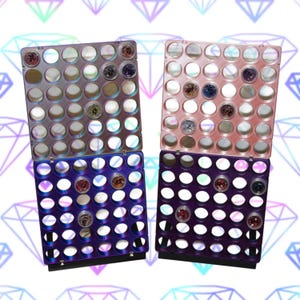 Op de afbeelding: Vier kleurrijke, verbonden trays met ronde compartimenten, elk met kleine decoratieve items. De trays zijn in tinten roze, paars en blauw, met een diamantpatroon op de achtergrond. De items in de compartimenten variëren in kleur en textuur.
