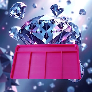 Puede incluir: Una bandeja de manualidades rosa brillante con cuatro secciones divididas. La bandeja es rectangular con esquinas redondeadas y un borde elevado. Grandes ilustraciones de diamantes brillantes en el fondo, creando un tema glamuroso.
