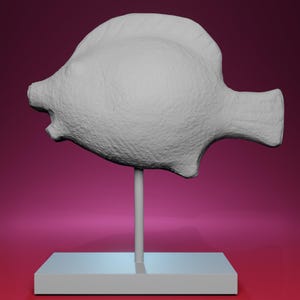 May include: A white, textured fish sculpture mounted on a thin, vertical rod, which is attached to a rectangular base. The fish has a rounded body and a small tail fin. The background is a gradient of pink and purple.