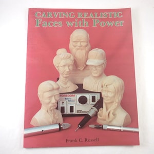 May include: A book titled "CARVING REALISTIC Faces with Power" on a red background. The cover features carved wooden faces and a carving tool. The author's name, Frank C. Russell, is at the bottom.