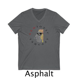 Peut inclure: T-shirt col en V gris asphalte avec un graphisme de profil portant des lunettes de soleil pixélisées et fumant une cigarette. Le t-shirt porte les mots "SEMIOTIC APPAREL" dans un design circulaire. Le mot "Asphalt" est imprimé en bas.