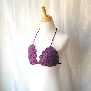 May include: Purple crochet bikini top with scalloped edges. The top is on a white mannequin.