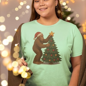 Christmas Bigfoot Tee - Festive Humor Shirt, Sasquatch Christmas Gift, Unisex Holiday T-Shirt, Fun Xmas Apparel, Cute Bigfoot Decor
