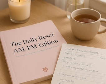 May include: A self-care scene featuring a lit candle in a glass, a pink journal titled "The Daily Reset AM/PM Edition", a notepad with handwritten notes, a pen, a mug of tea, and a vase with white flowers. The journal's text reads "A SELF CARE RITUAL FOR MINDFUL MORNINGS AND RESTFUL NIGHTS."