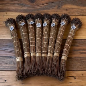 Peut inclure: Sept bouquets d'aiguilles de pin séchées, solidement liés avec de la ficelle naturelle. Chaque bouquet porte une petite étiquette. Les bouquets sont disposés sur une surface en bois, mettant en valeur les textures et couleurs naturelles.