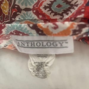 May include: Close-up of a fabric with a colorful, intricate pattern in shades of red, blue, orange, and white. The fabric has a tag that reads "ANTHOLOGY".