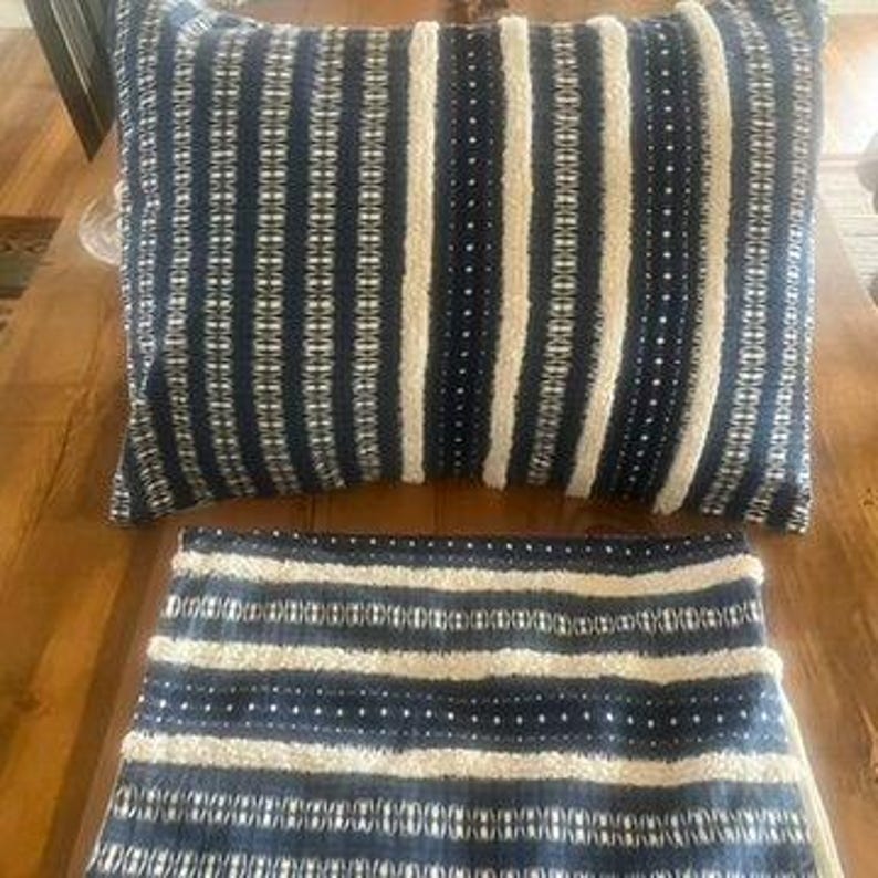 May include: A rectangular decorative pillow and a matching throw blanket. Both items feature a navy blue and white striped pattern. The pillow is approximately 20 inches long and 12 inches wide. The blanket is folded and visible in the image.