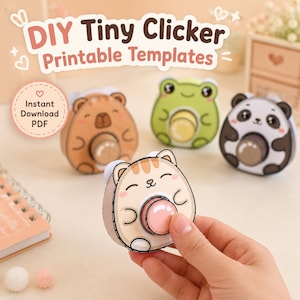 May include: DIY Tiny Clicker Printable Templates PDF. Four paper craft clickers featuring cartoon animals: a brown bear, a green frog, a black and white panda, and a tan cat with a pink button center. Each animal has a round shape and a push button.