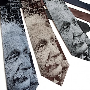 May include: A collection of neckties featuring a detailed illustration of Albert Einstein's face. The ties vary in color, including black, brown, and gray, with the portrait in a contrasting lighter shade. Some ties have scientific formulas in the background.