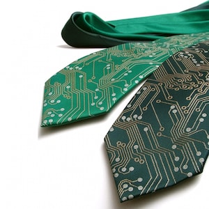 May include: Three green neckties featuring a circuit board pattern. The ties are in shades of green with gold and silver detailing. One tie is folded, while the other two display the intricate circuit board design.