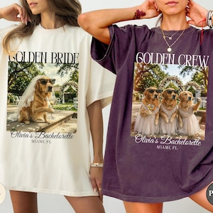 May include: Two oversized t-shirts in ivory and pepper colors. The ivory shirt features a golden retriever in a veil and sunglasses with the text GOLDEN BRIDE and Olivia's Bachelorette MIAMI, FL. The pepper shirt shows three golden retrievers in dresses with the text GOLDEN CREW and Olivia's Bachelorette MIAMI, FL.