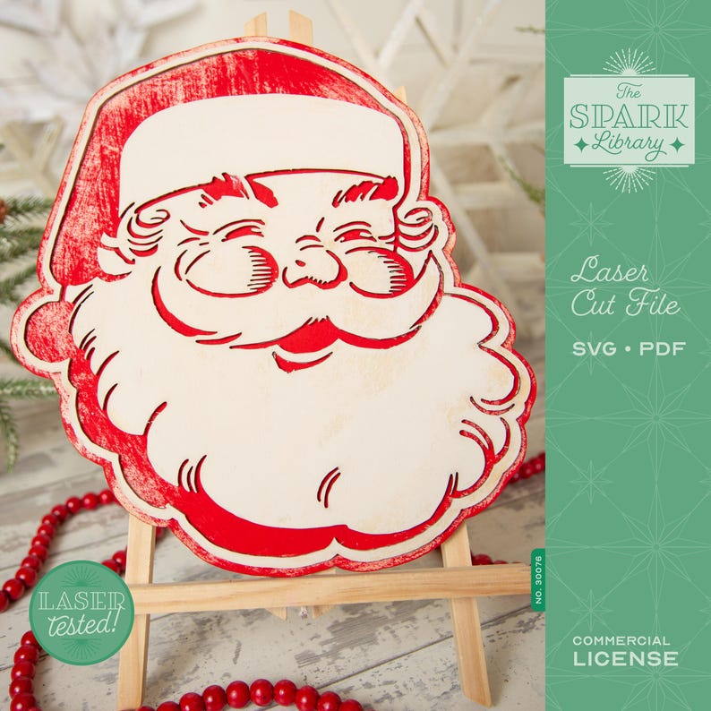 May include: A red and white laser-cut Santa Claus face displayed on a small wooden easel. The design features a smiling Santa with a red hat and beard. The image includes text that reads "Laser Cut File" and "Commercial License."