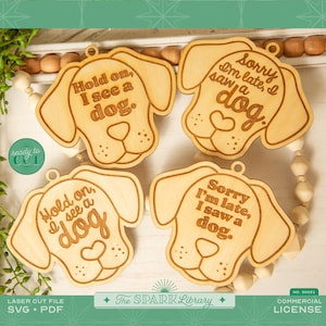 May include: Four wooden ornaments shaped like dog heads with different sayings. The sayings are "Hold on, I see a dog", "Sorry I'm late, I saw a dog", "Hold on, I see a dog", and "Sorry I'm late, I saw a dog".