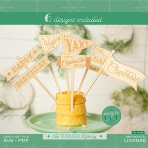 Puede incluir: Seis adornos de pastel de madera con frases de celebración como "Happy Birthday" y "Cheers!". Los adornos están insertados en un pastel pequeño sobre un plato verde. La imagen incluye texto que dice "6 diseños incluidos" y "ready to cut".