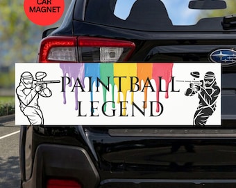 May include: A rectangular car magnet featuring a white background with a rainbow-colored paint drip design. The text PAINTBALL LEGEND is printed in black, flanked by black line-art illustrations of two paintball players aiming their markers.